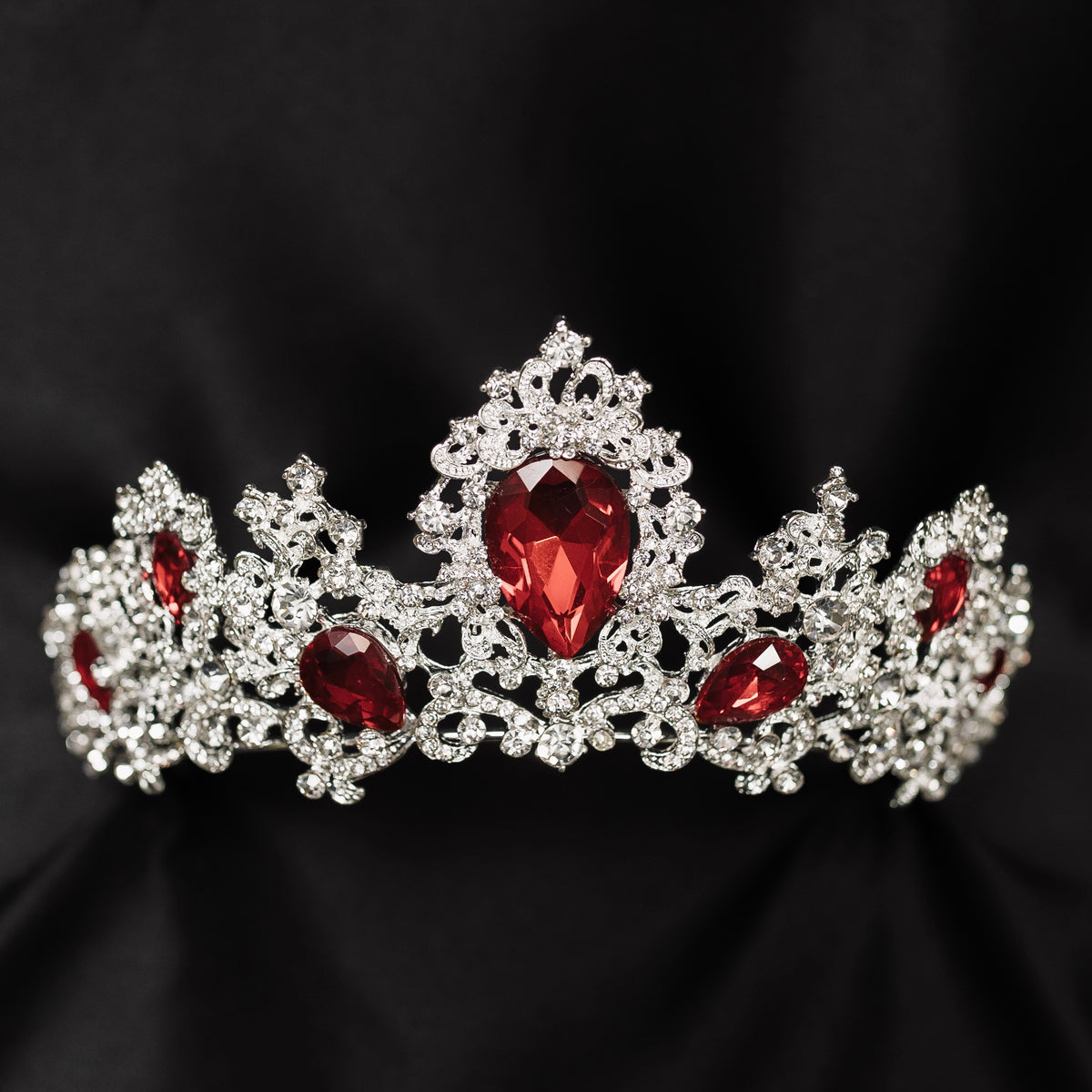 A tiara adorned with silver white gold colored sparkles and large marquise shaped red crystals.