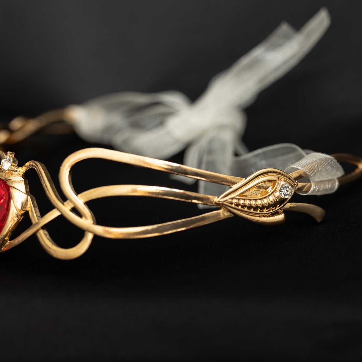 Gold hair clip with red gemstone and clear ribbon on a black background