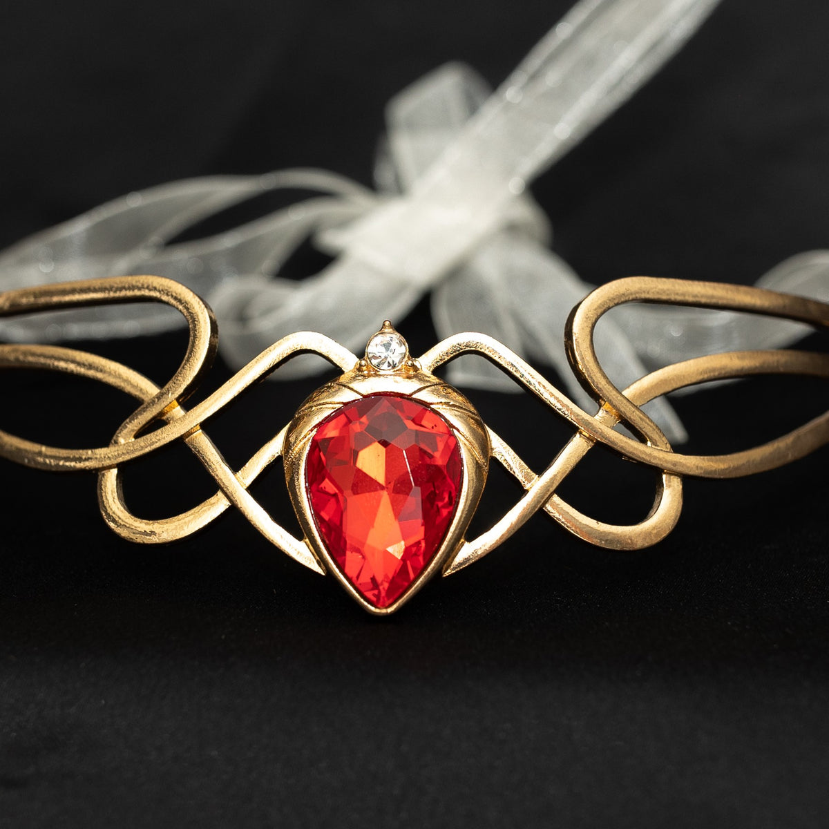Gold bracelet with a red gemstone on a dark background