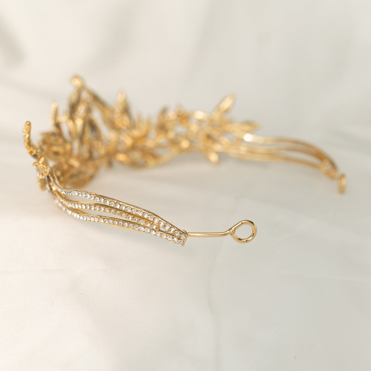 A golden tiara with red crystal embellishments and leaf detailing, displayed against a white background. - Looped End View