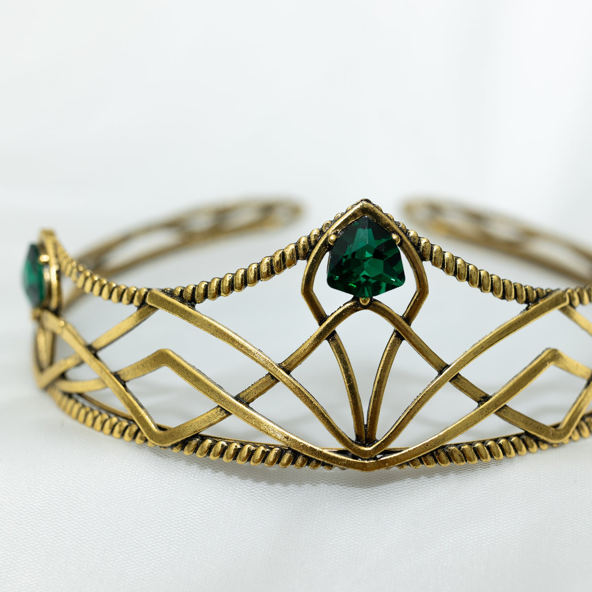 emerald crystal three point green gem on gold crown with curving designs and detailed edges - Close Up Center Side