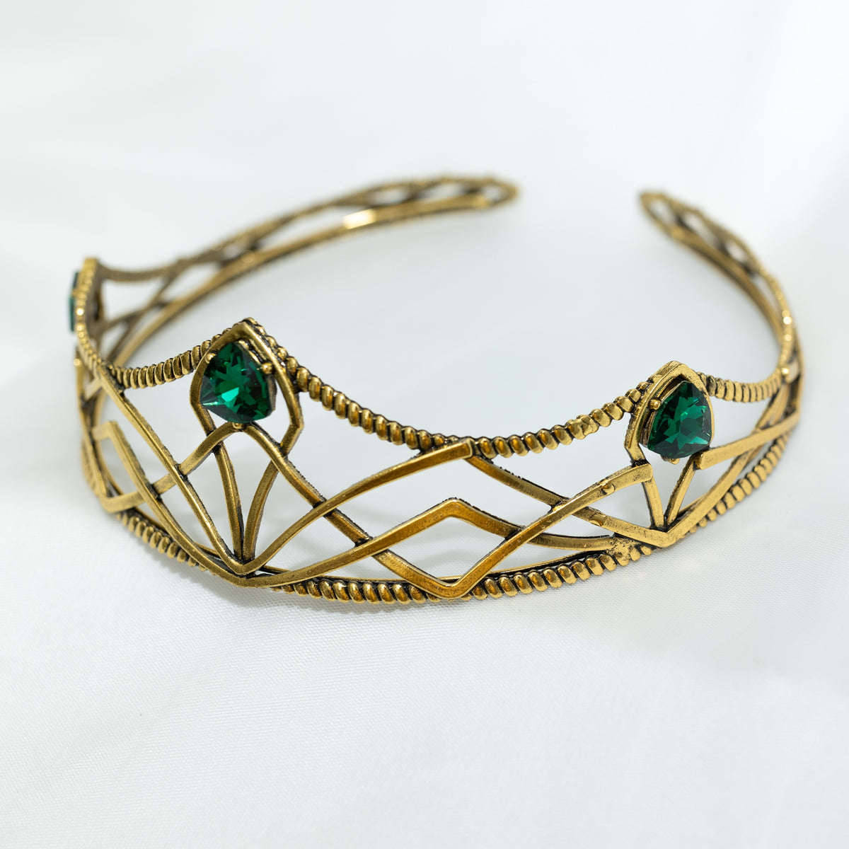 emerald crystal three point green gem on gold crown with curving designs and detailed edges - Angle Front View