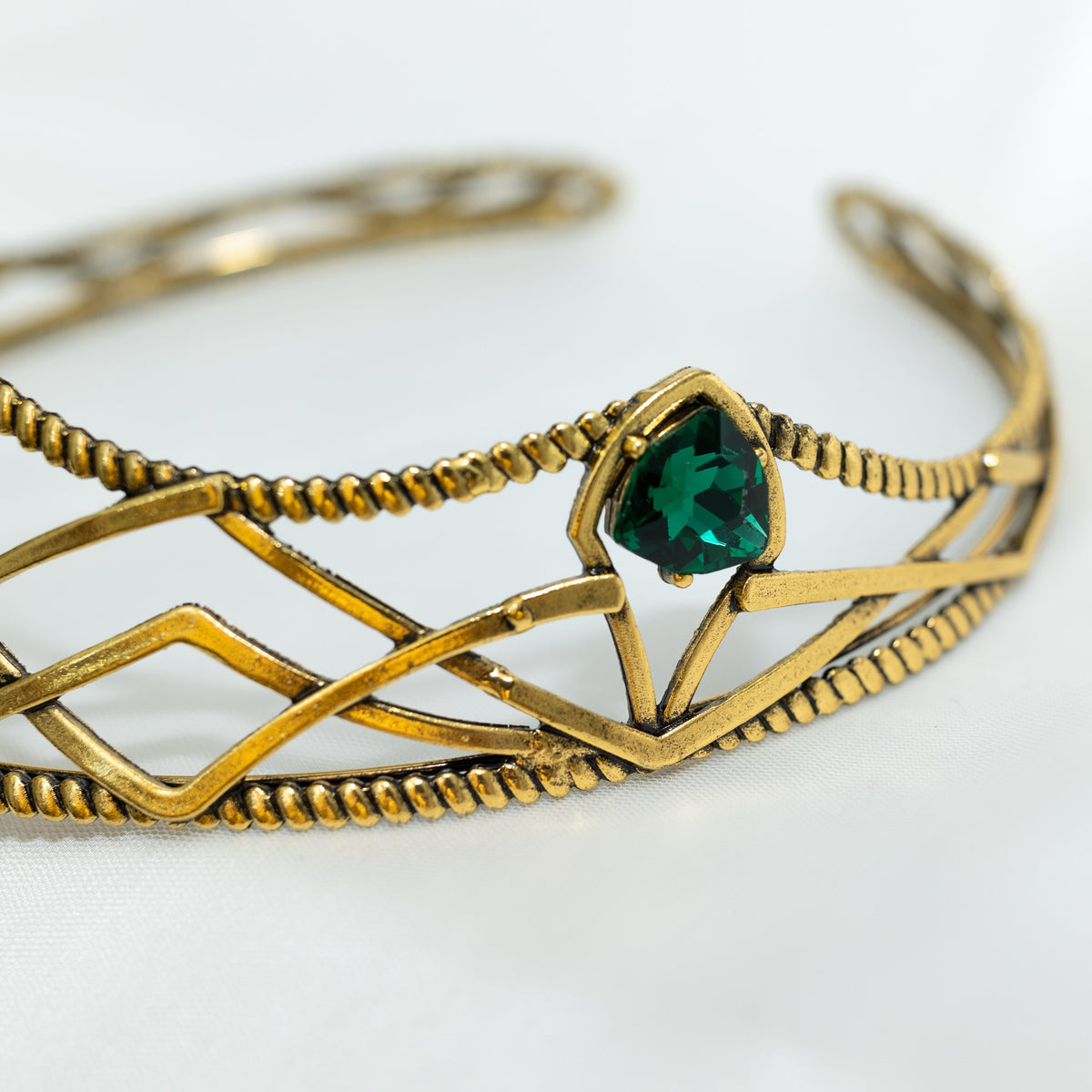 emerald crystal three point green gem on gold crown with curving designs and detailed edges - Close up Of Side