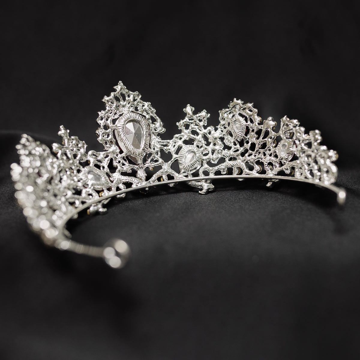 A tiara adorned with silver white gold colored sparkles and large marquise shaped red crystals. rear view