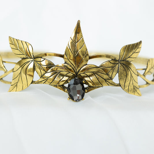 A gray and gold tiara with laurel leaf detailing and a central gray stone, displayed against a white background. Front close up view