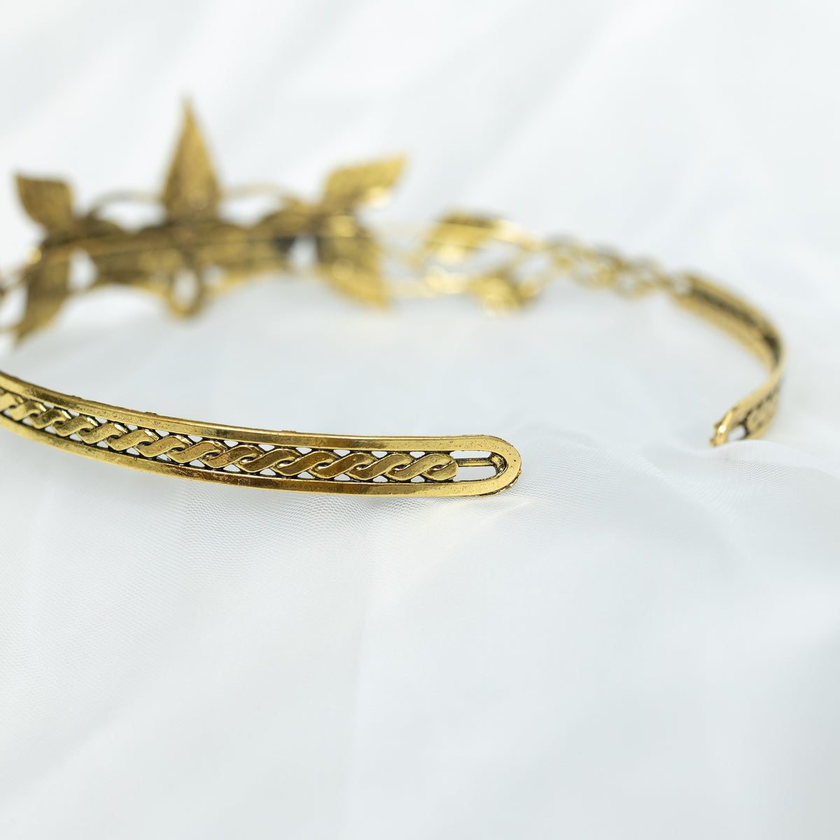 A gray and gold tiara with laurel leaf detailing and a central gray stone, displayed against a white background. Rear view