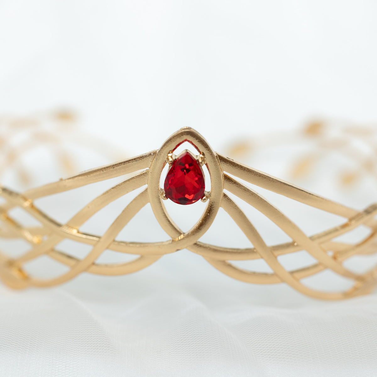 Gold bracelet with a red gemstone on a white background