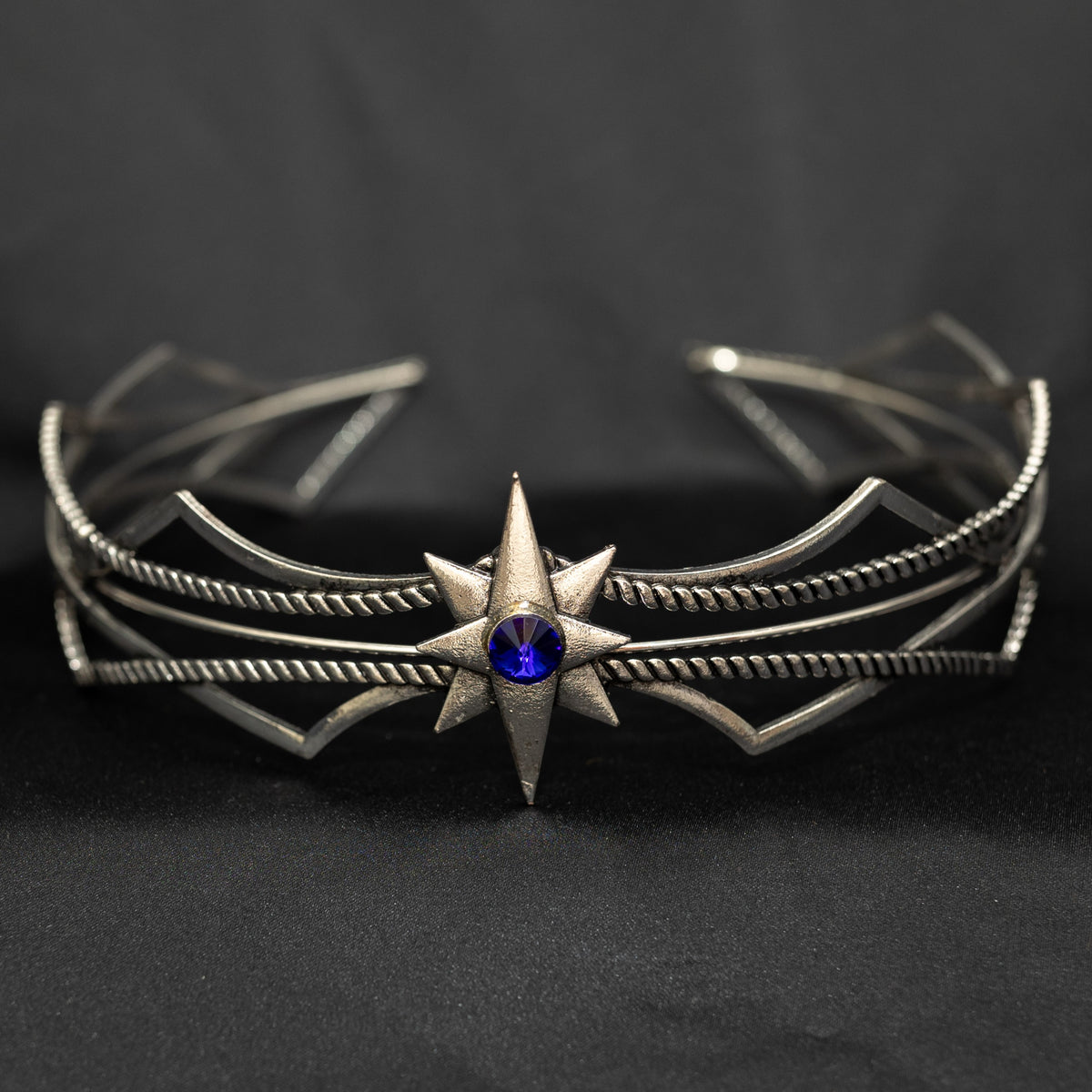 Silver bracelet with star design and blue gemstone on a dark background