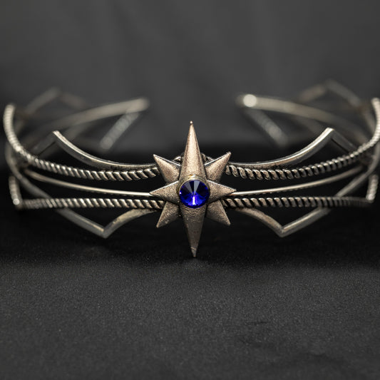 Silver bracelet with star design and blue gemstone on a dark background
