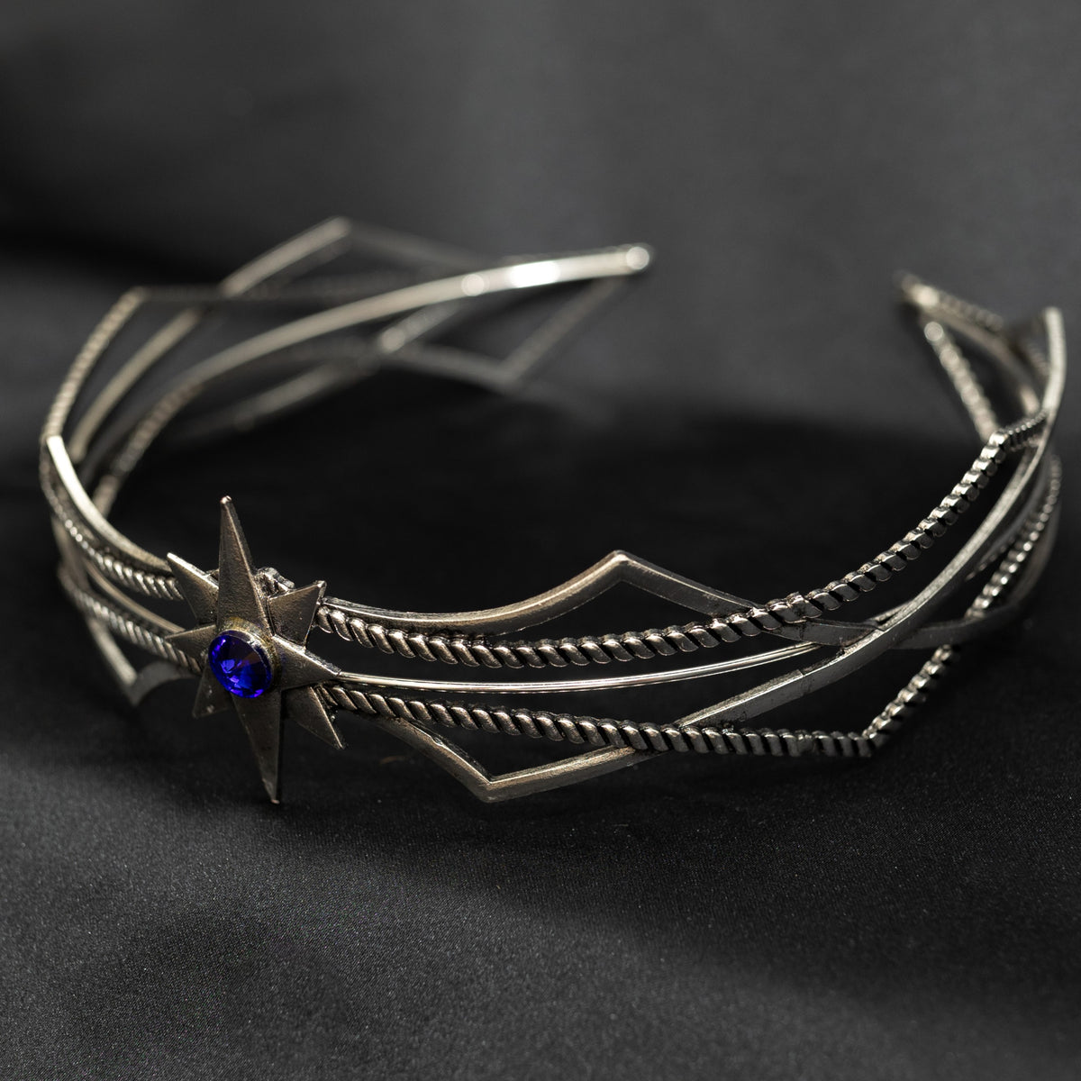 Silver bracelet with a blue gemstone on a black background