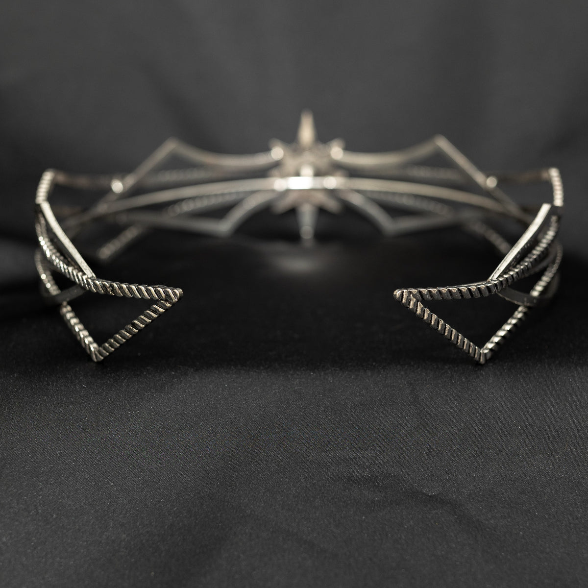 Silver spiderweb-shaped tiara on a black background