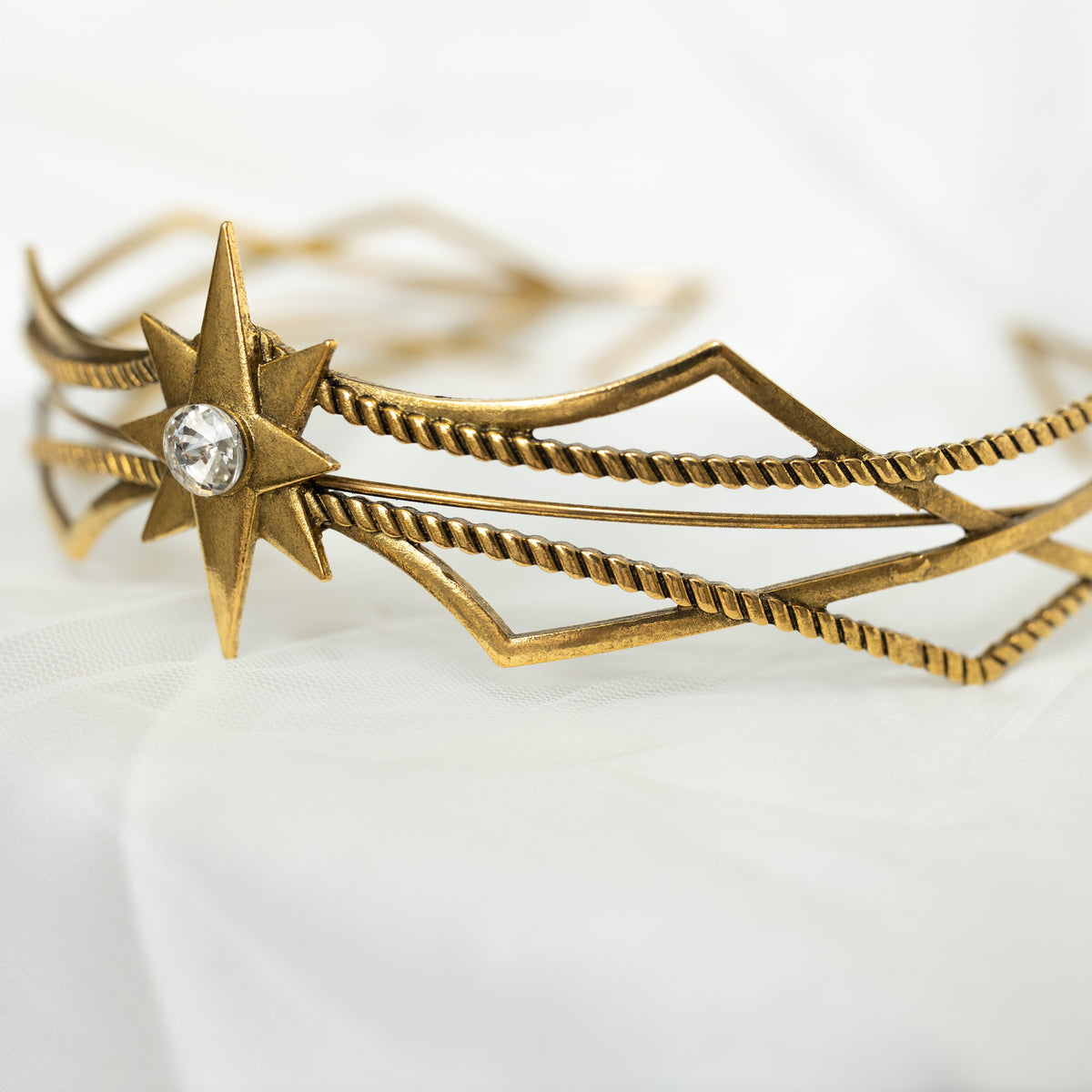 Gold star-shaped headband with a central gemstone on a white background