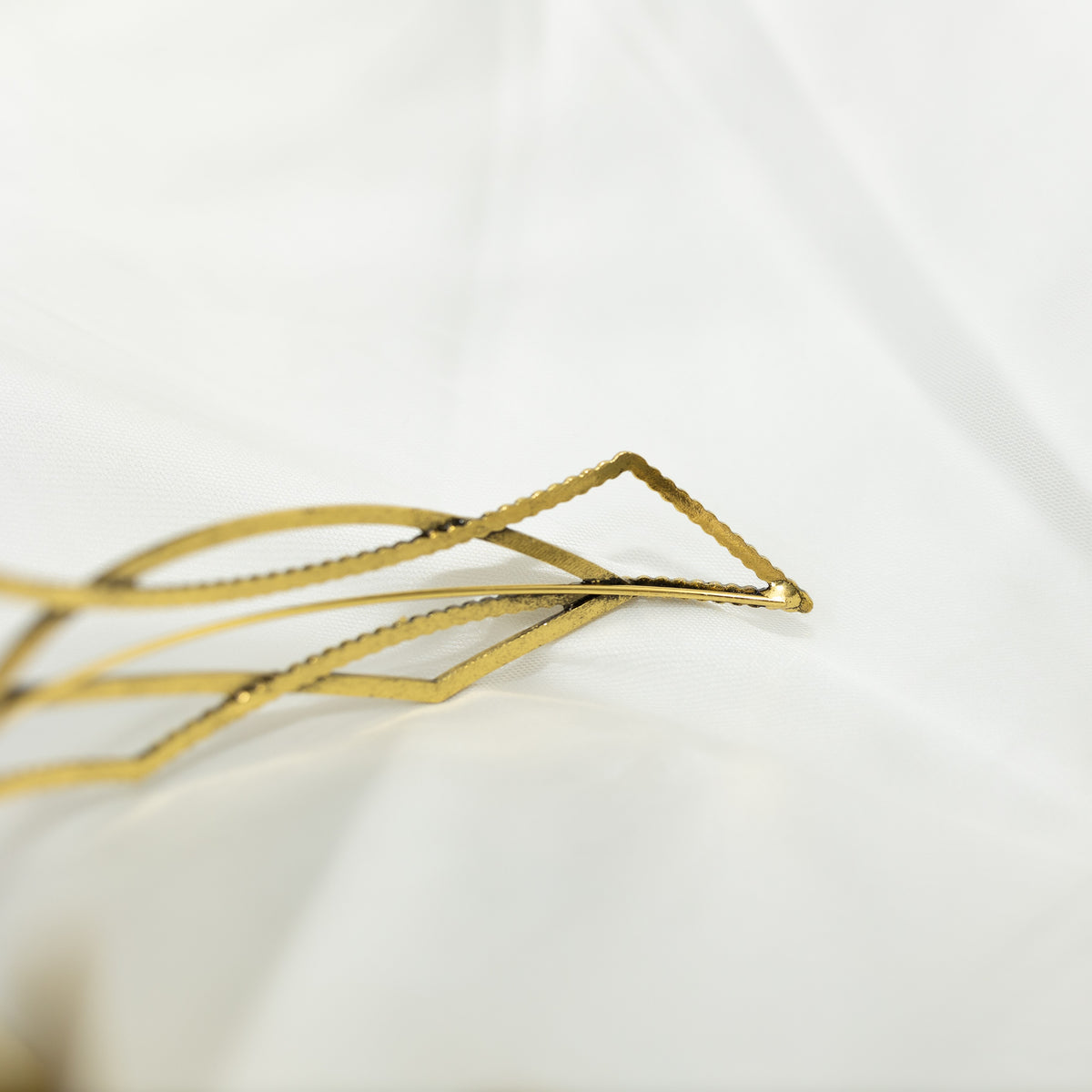 Gold geometric hair clip on a white background