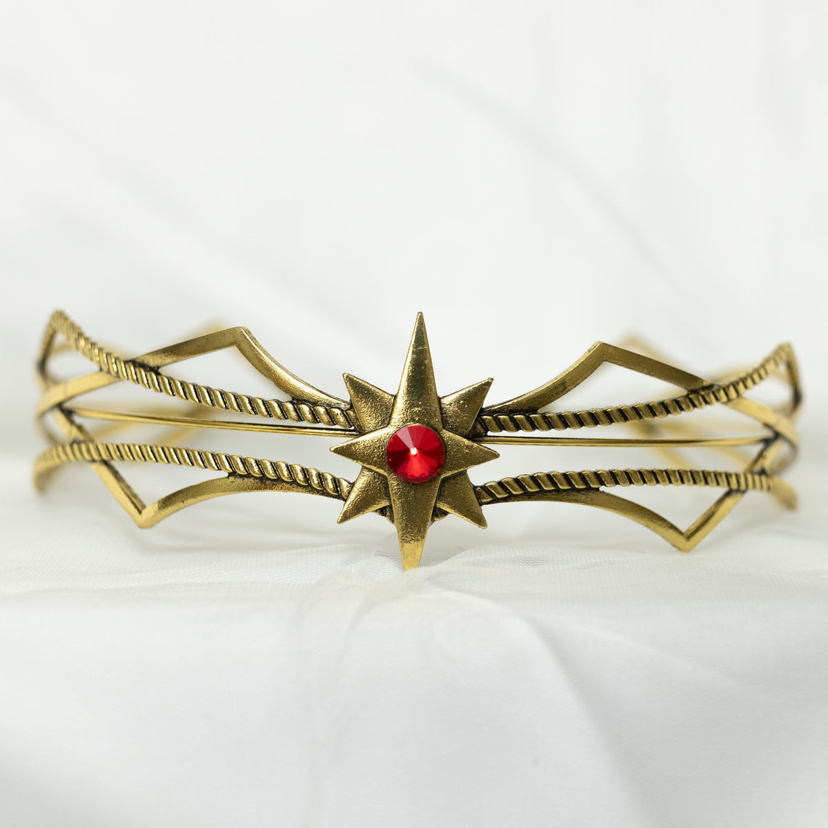 Gold bracelet with a red gemstone on a white background