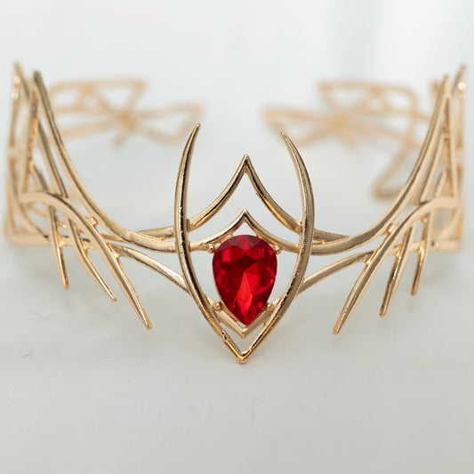 Gold bracelet with a red gemstone on a light background