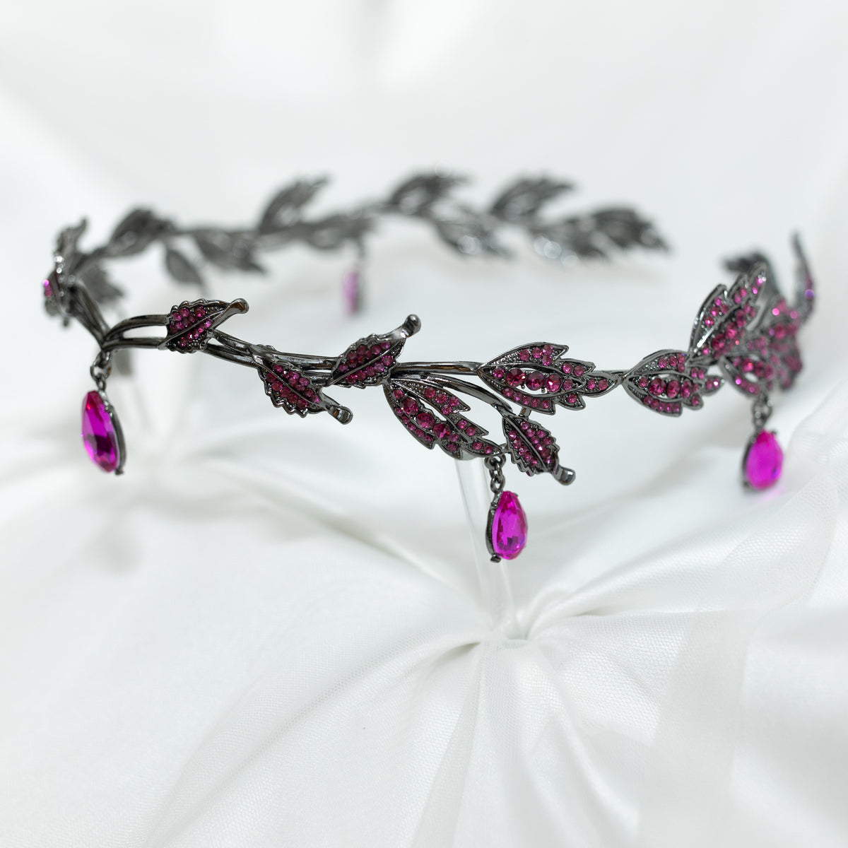An elegant circlet featuring a hot pink crystal drop as the centerpiece, antique silver color metal with leaf-shaped embellishments and smaller pink crystals, set against a white background.