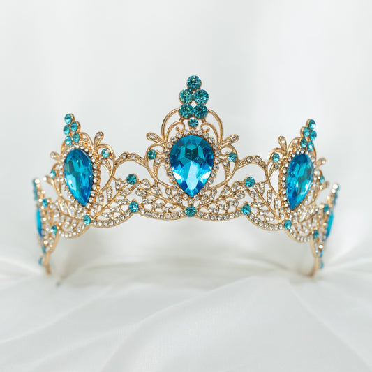 Gold tiara with blue gemstones on a white background