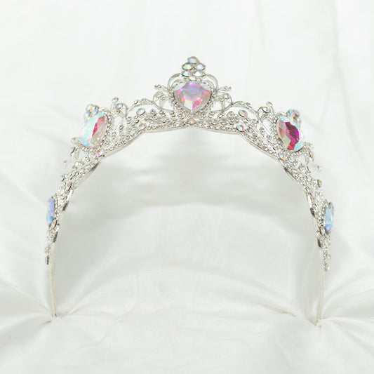 Silver tiara with colorful gemstones on a white cushion