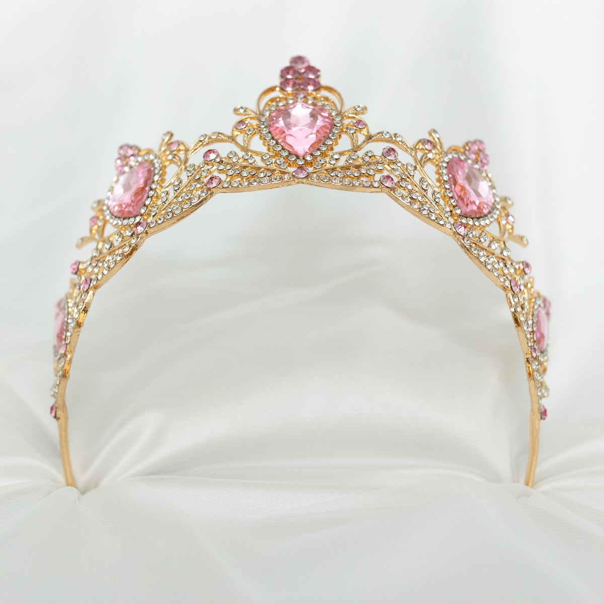 Gold tiara with pink gemstones on a white background