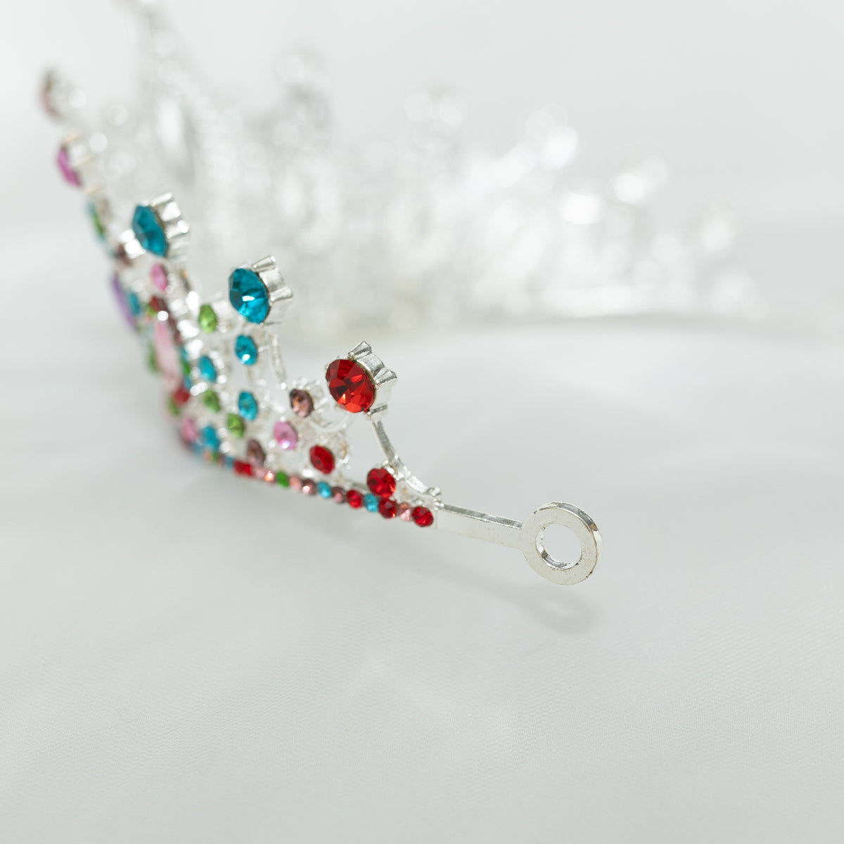 Decorative tiara with colorful gemstones on a light gray background