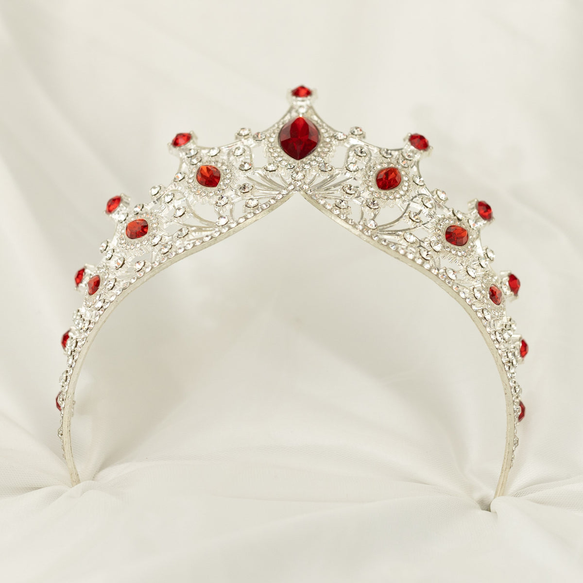 Silver tiara with red gemstones on a white background