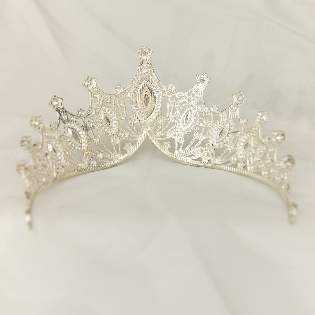 Silver tiara with intricate design on a light gray background