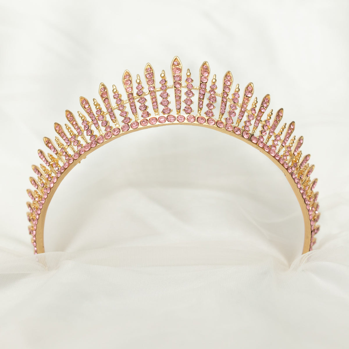A pink and gold tiara with a spire design, featuring clear crystals. Bottom view