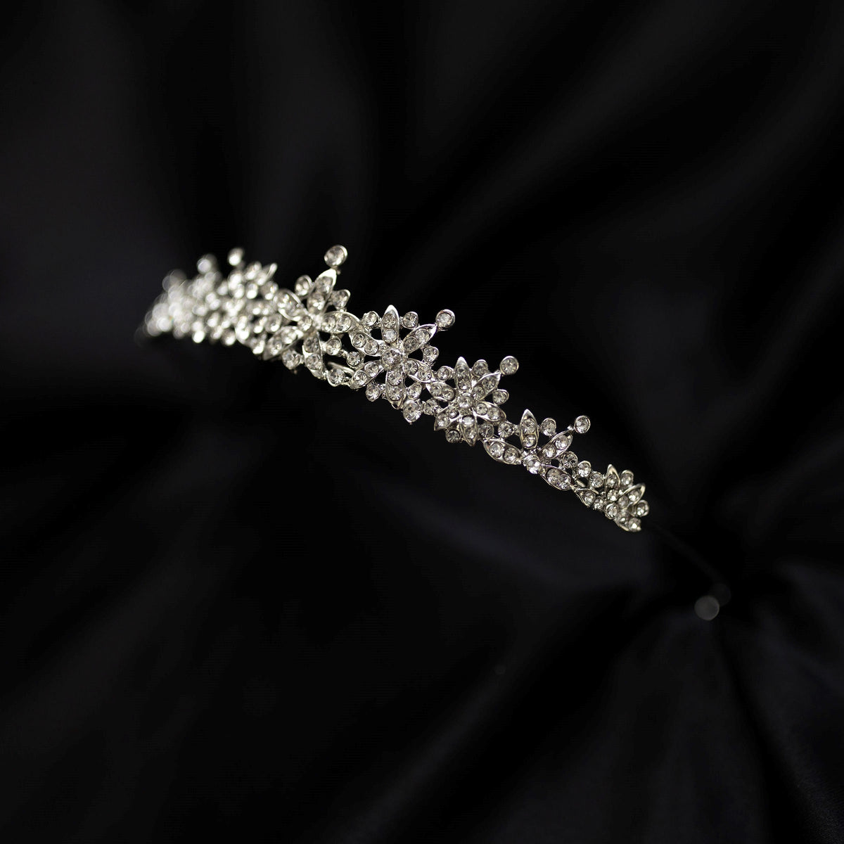 Silver tiara on black background - small crystals with silver metal details in triangular shape - side angle view