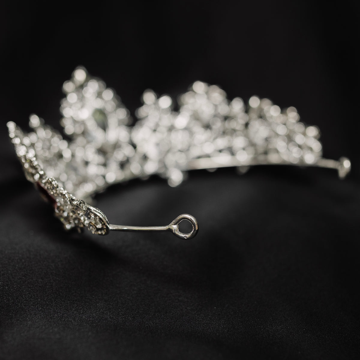 A tiara adorned with silver white gold colored sparkles and large marquise shaped red crystals. looped end 