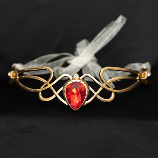 Gold brooch with a red gemstone on a dark background