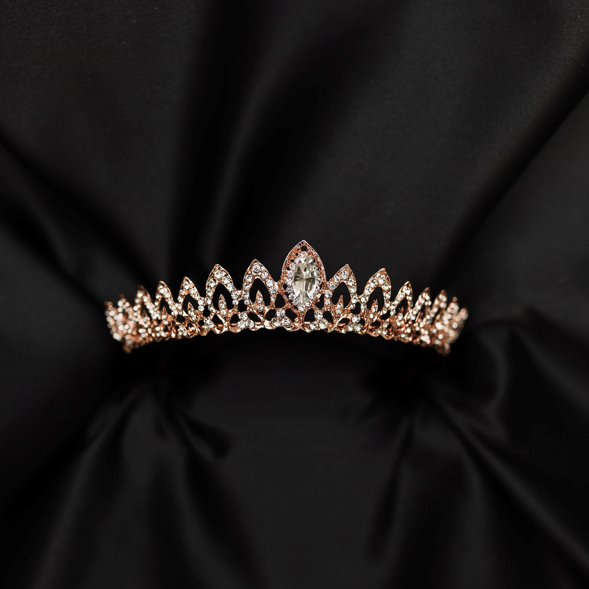 Rose gold tiara with clear gemstones on a black satin background