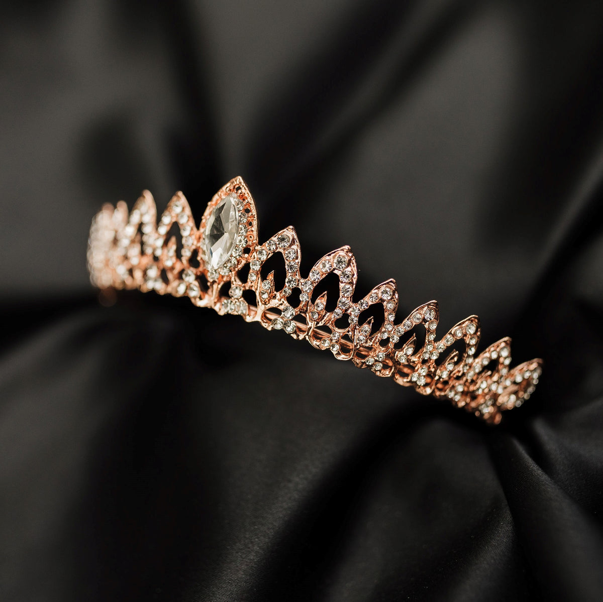 Rose gold tiara with clear gemstone on a black satin background