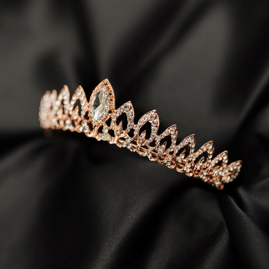 Rose gold tiara with clear gemstone on a black satin background