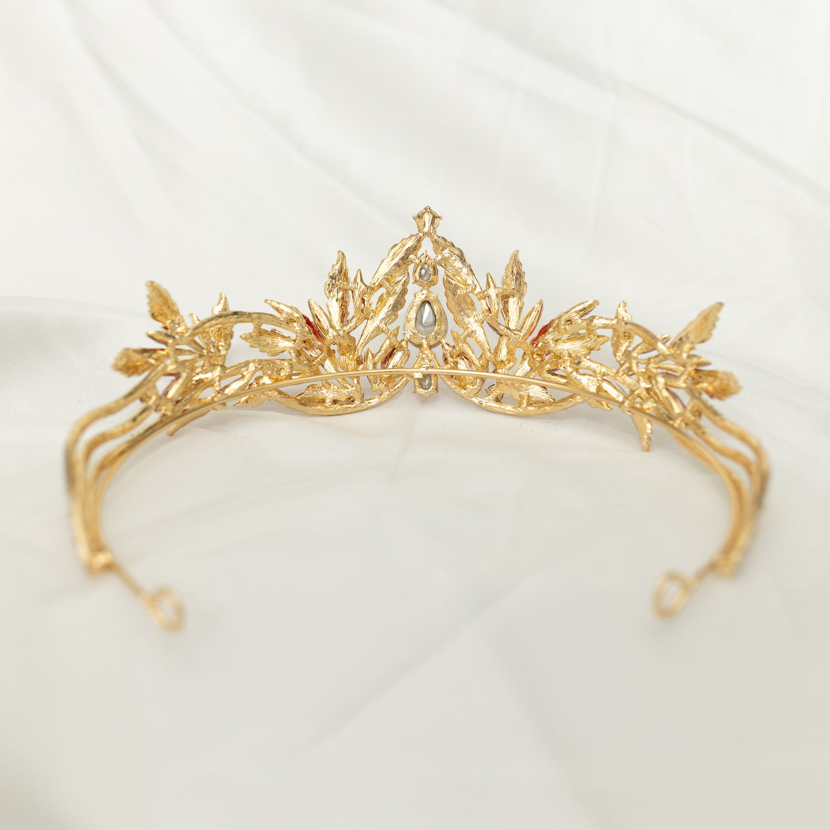 A golden tiara with red crystal embellishments and leaf detailing, displayed against a white background. - Back View