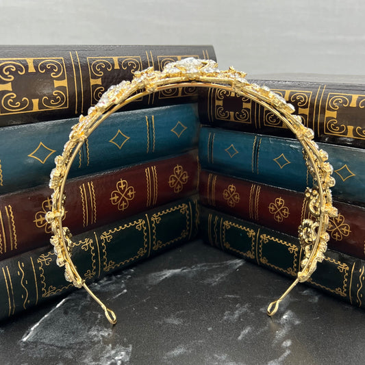 Gold headband with pearls on a stack of decorative books