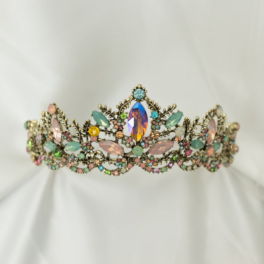 An antique gold-colored tiara adorned with large blue and pink crystals, and accented with pink, peach, blue, and turquoise color crystals. Front View