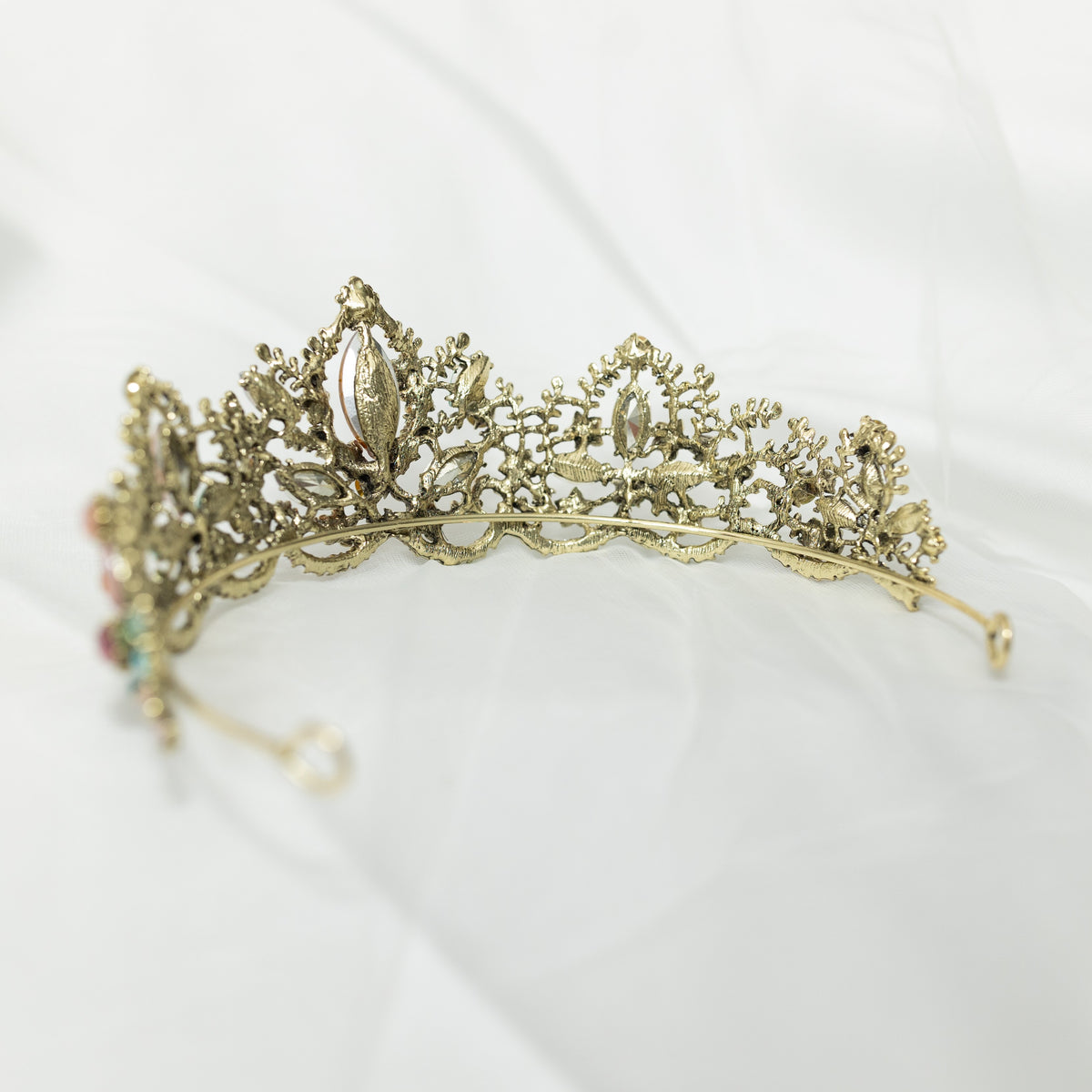 An antique gold-colored tiara adorned with large blue and pink crystals, and accented with pink, peach, blue, and turquoise color crystals. Rear View