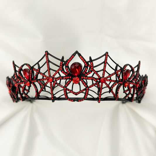 A sparkling tiara featuring a black spider web design with red crystals and a central red crystal, displayed on a white background.