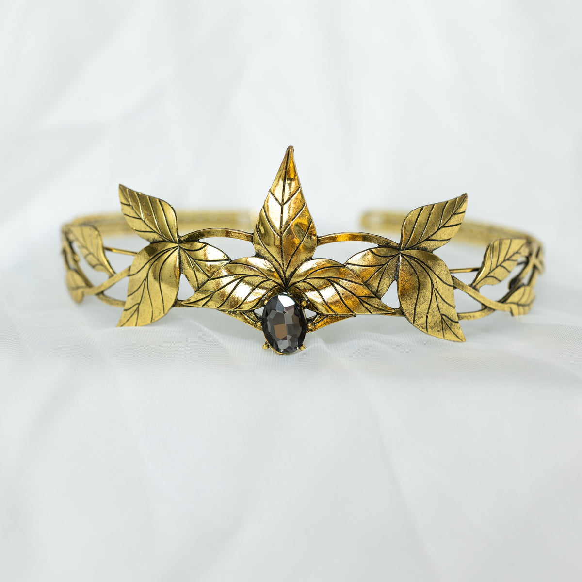 A gray and gold tiara with laurel leaf detailing and a central gray stone, displayed against a white background. Front view 