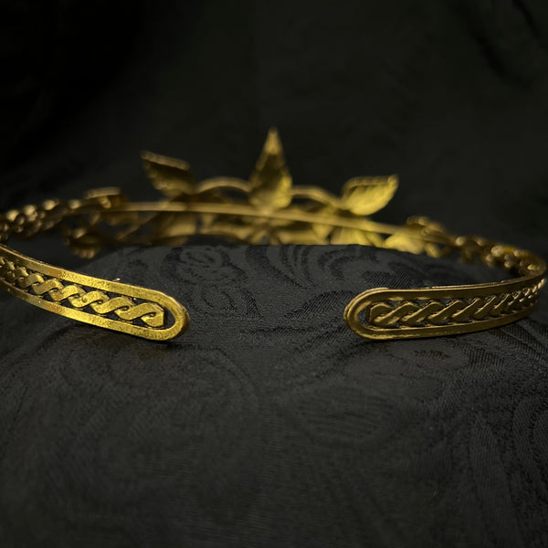 Close-up of ornate gold-toned decorative hardware or trim attached to a black textured fabric surface.