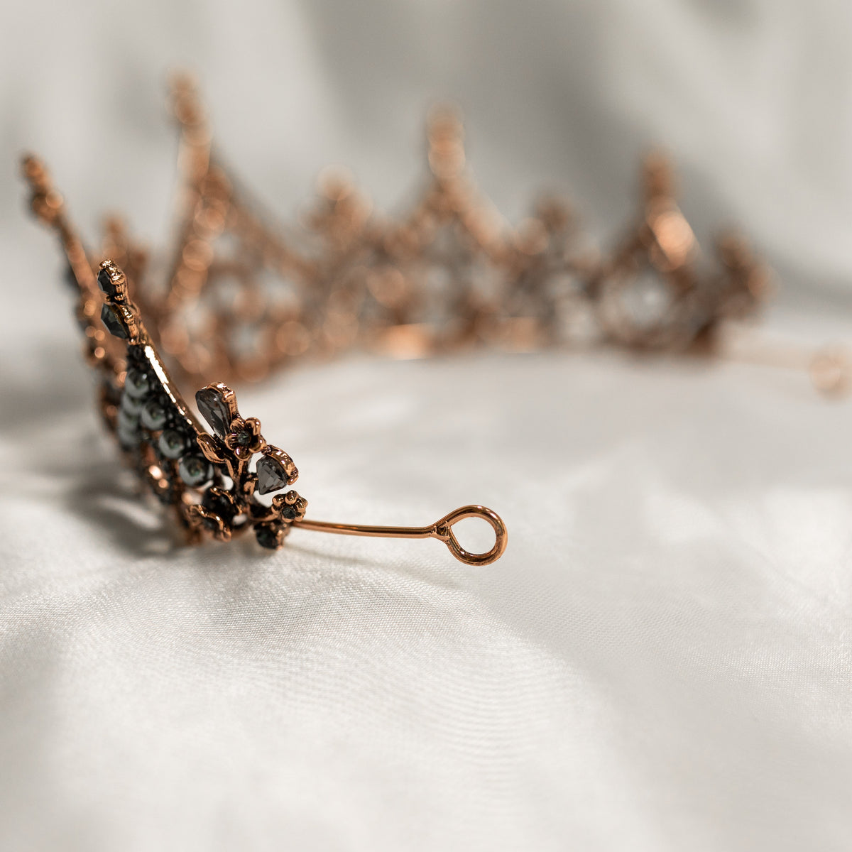 Rose gold hair clip with black gemstones on a white fabric background