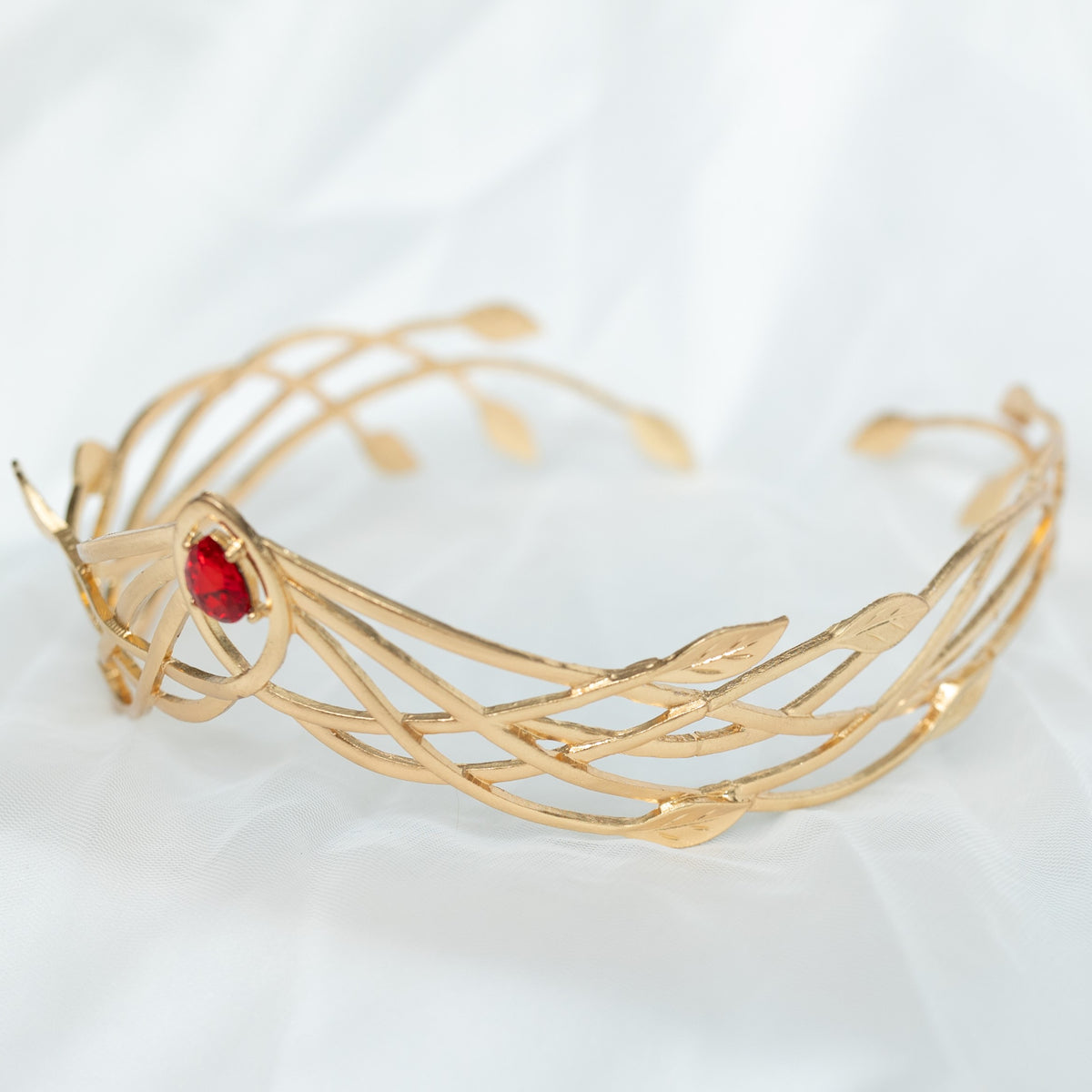 Gold bracelet with red gemstone on a light background