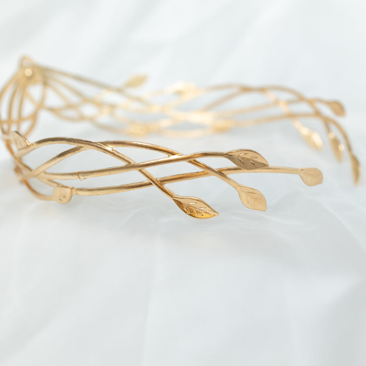 Gold bracelet with leaf designs on a light background