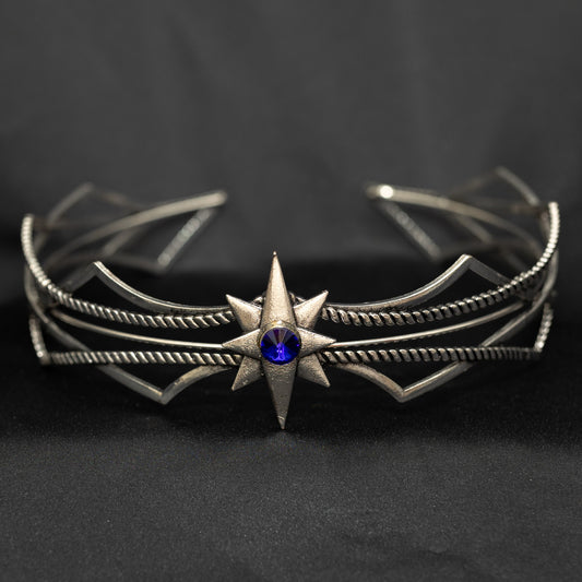Silver bracelet with star design and blue gemstone on a dark background