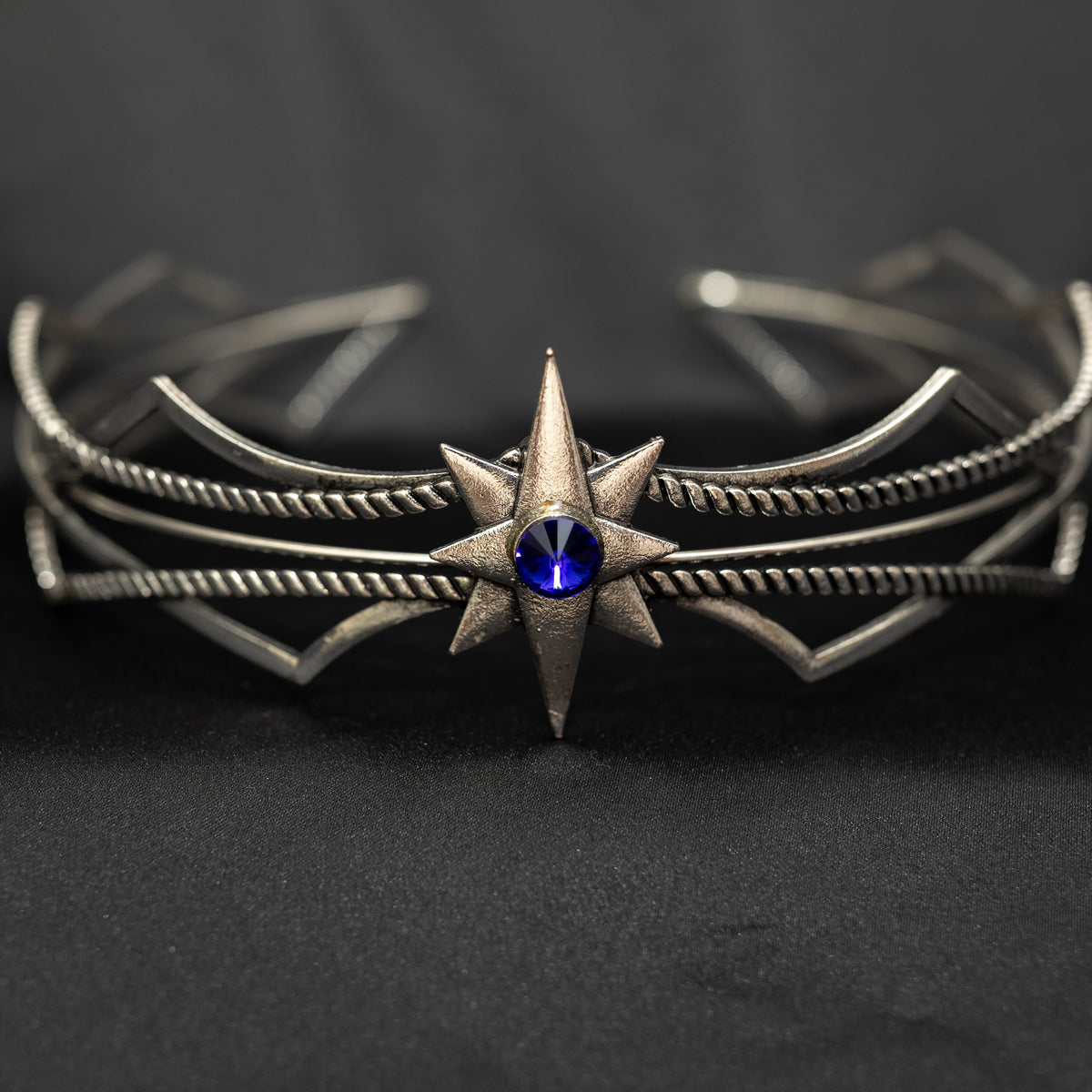 Silver bracelet with star design and blue gemstone on a dark background