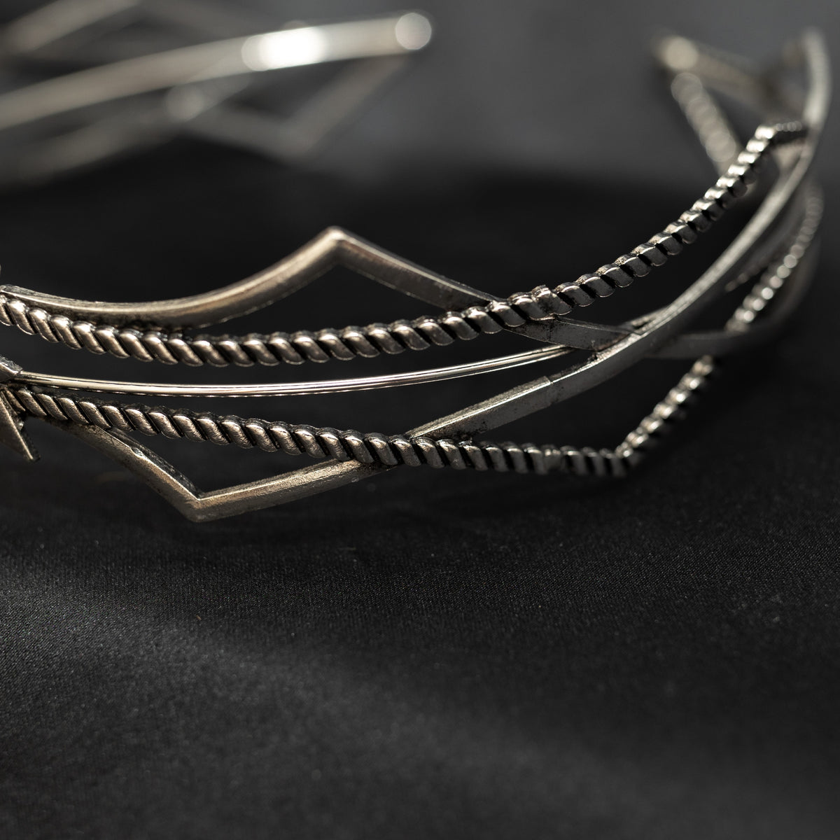 Silver bracelet with geometric design on a dark background