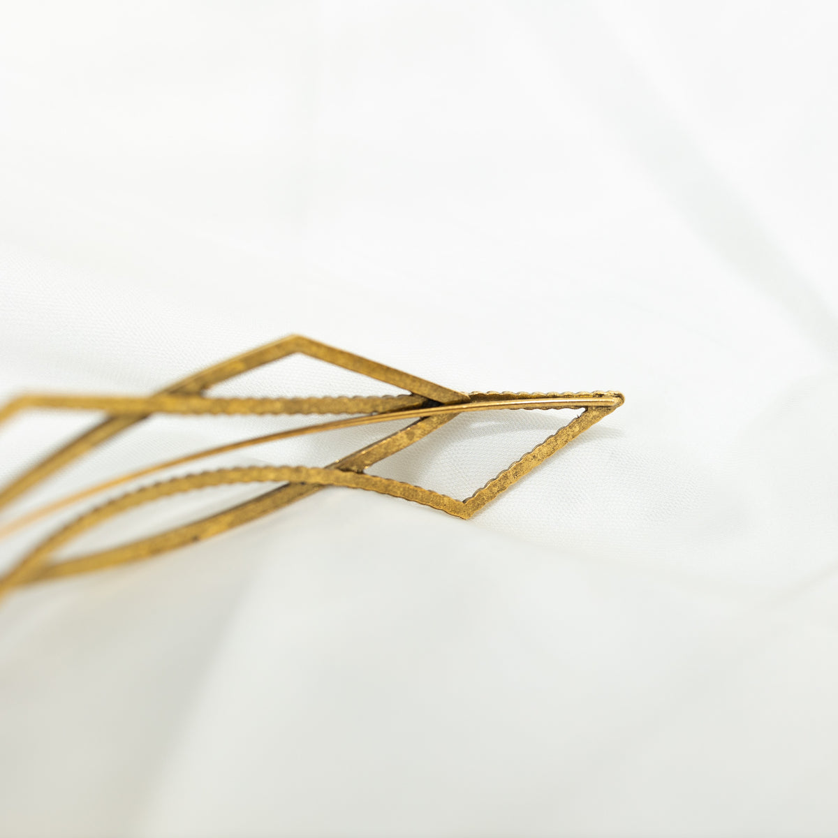 Gold geometric hairpin on a white background