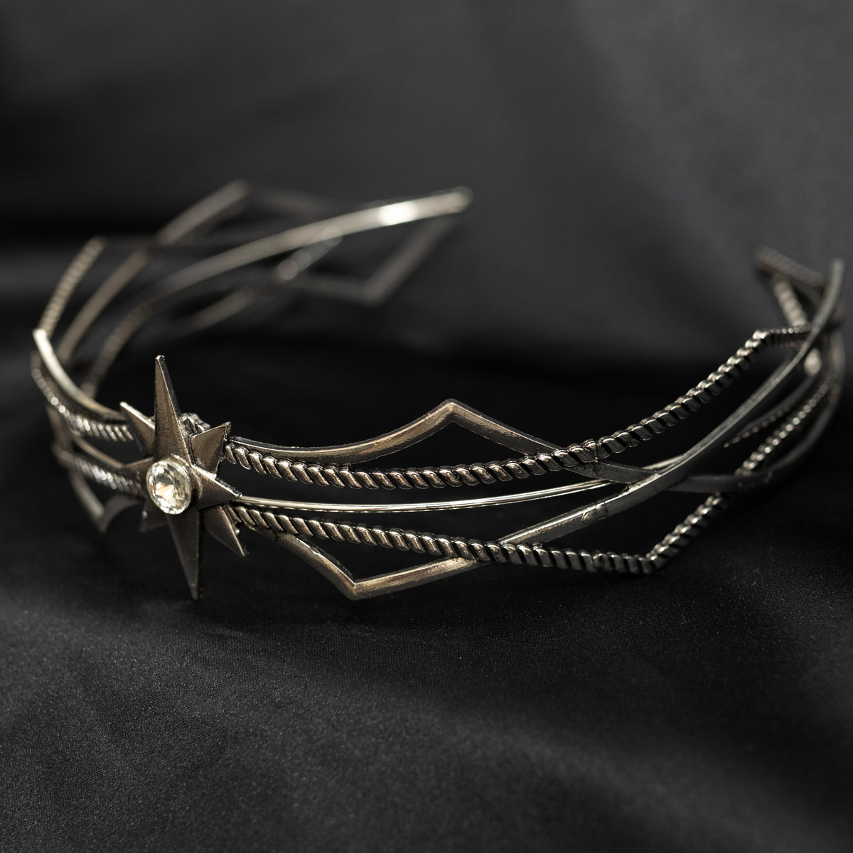 Silver star-shaped headpiece on a black background w/ central clear crystal - Side front view