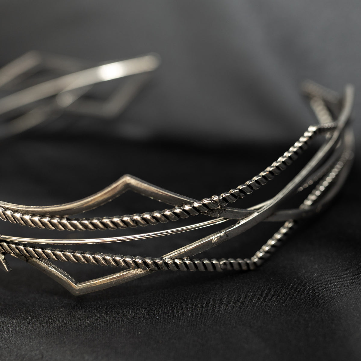 Silver star-shaped headpiece on a black background w/ central clear crystal - close up side view 