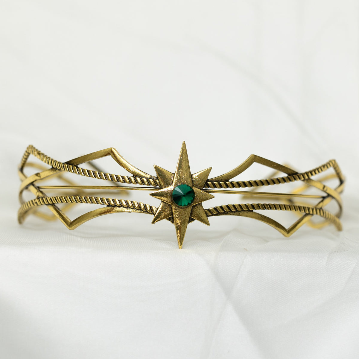 Gold bracelet with a green gemstone on a white background